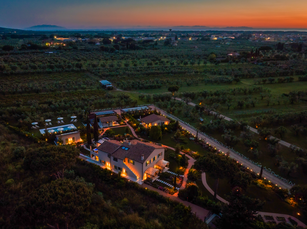 Terre dei Ghelfi au coucher du soleil, nichée au milieu de ses vignobles et oliveraies, avec vue sur la mer et les îles d'Elbe et de Capraia en arrière-plan.